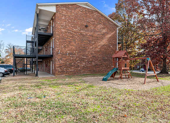 A red brick building with a playground in front.