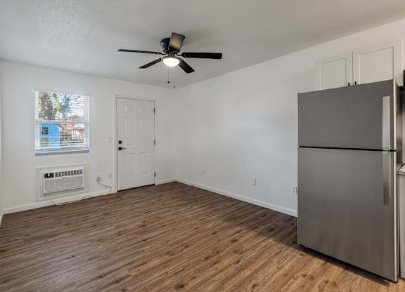 A room with a ceiling fan and a refrigerator.