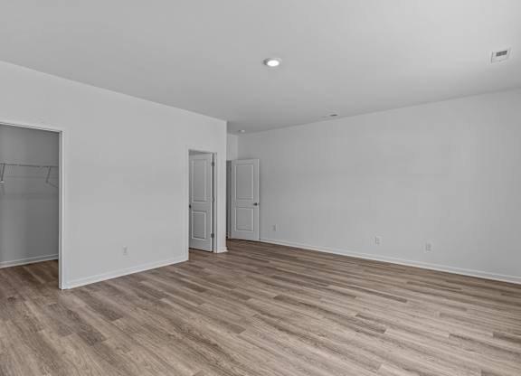 A room with white walls and wood flooring with two doors.