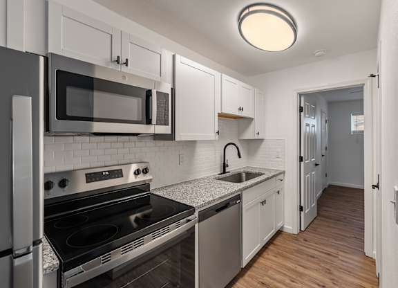 A kitchen with a stove, oven, microwave, and dishwasher.