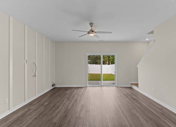 A room with a ceiling fan and wooden flooring.