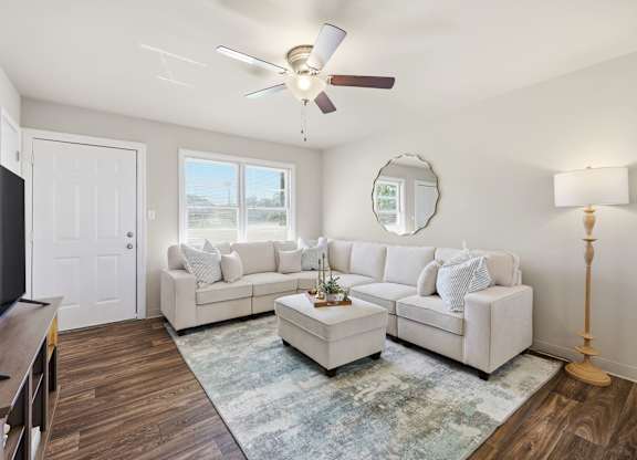 A living room with a white couch and a ceiling fan.
