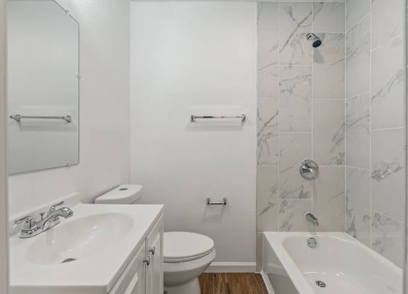 A white bathroom with a marble tile shower.