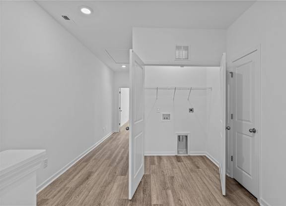 A white hallway with wood floors and a white door.