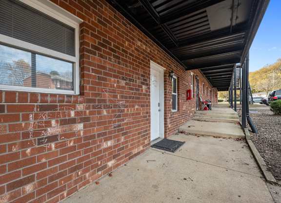 A red brick building with a white door and a window.
