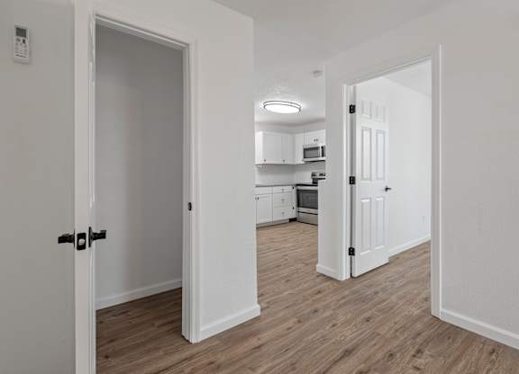a bedroom and a living room with a door open to a kitchen
