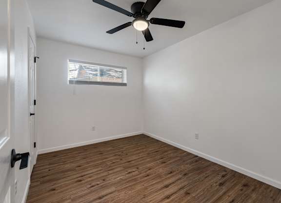 A room with a ceiling fan and wooden flooring.