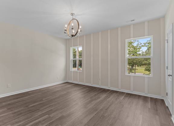 A room with wooden flooring and a chandelier.