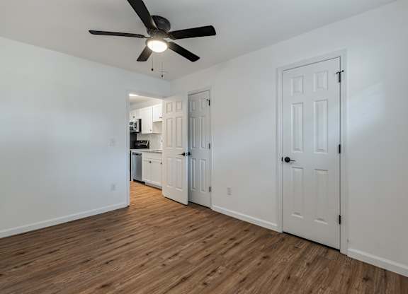 A room with a ceiling fan and wooden floors.