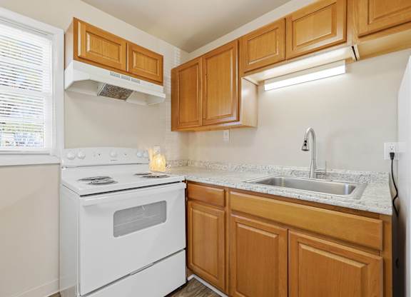 A kitchen with wooden cabinets and a white stove top oven.