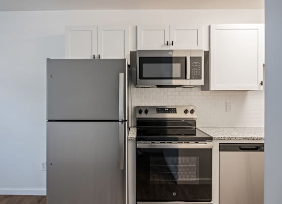 A kitchen with a stainless steel refrigerator, oven, and microwave.