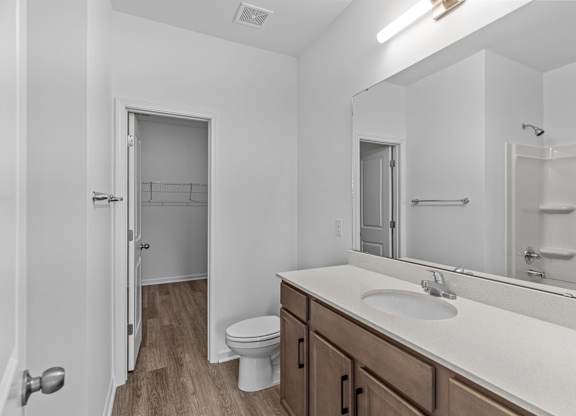 A white bathroom with a toilet, sink, and mirror.