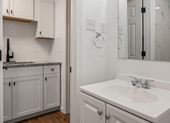 A white bathroom with a sink and a mirror.