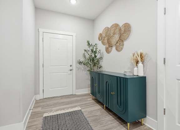 A white door is on the left of a room with a green cabinet.