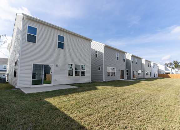 a row of white houses with a grassy yard