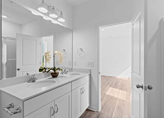 A bathroom with a white vanity and a mirror above it.