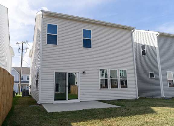 a white house with white siding and a patio in a yard