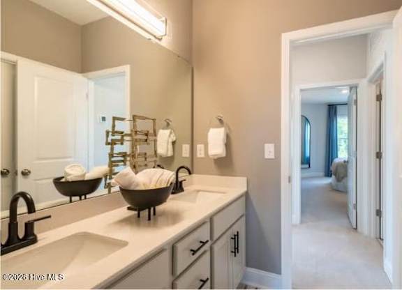 A bathroom with a sink, mirror, and a towel rack.
