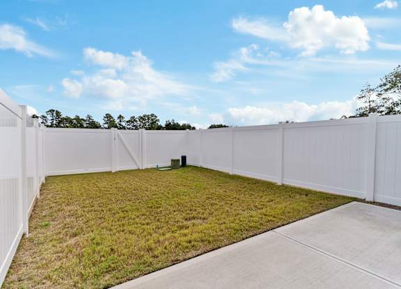 A white fence encloses a grassy area with a concrete pathway.
