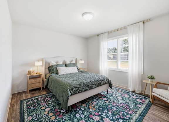 A bedroom with a bed, nightstands, and a rug.