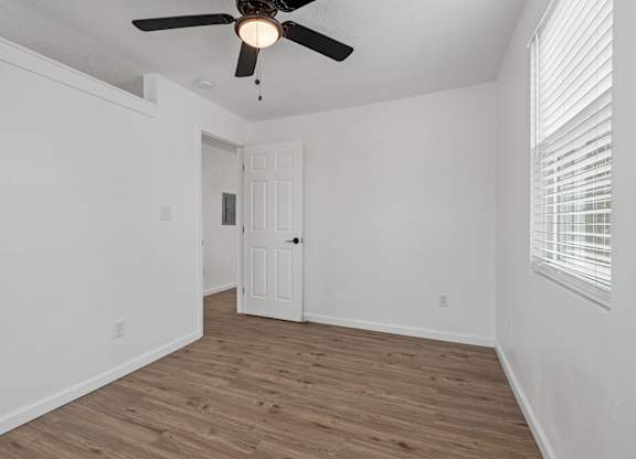 an empty bedroom with white walls and a ceiling fan