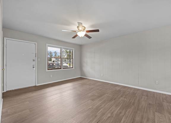 A room with a ceiling fan and wooden flooring.