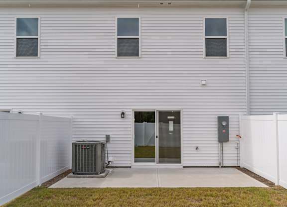 A white house with a grey fence and a grey air conditioner unit.
