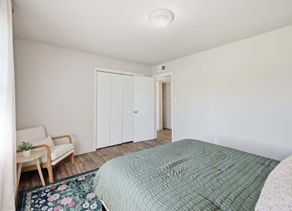 A bedroom with a bed, chair, and wardrobe.