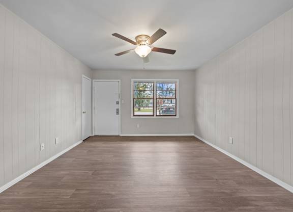A room with a ceiling fan and wooden flooring.