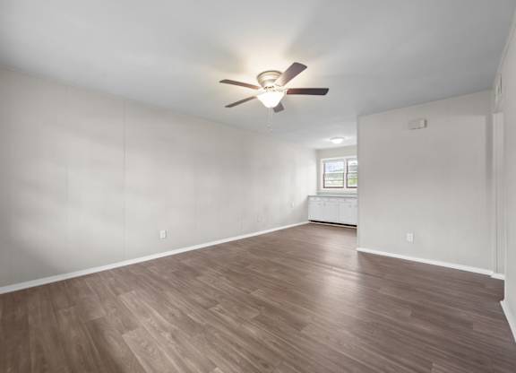 A room with a ceiling fan and wooden flooring.