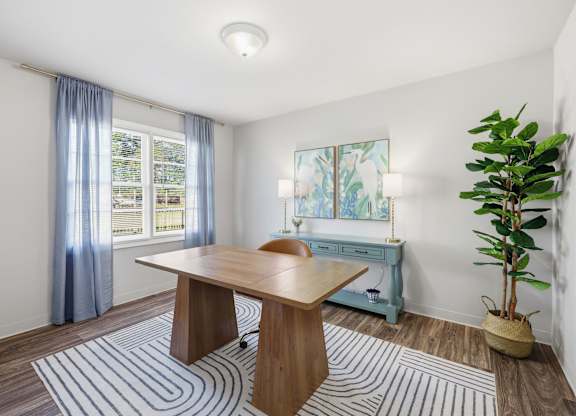 A room with a table, a plant, and a window with curtains.