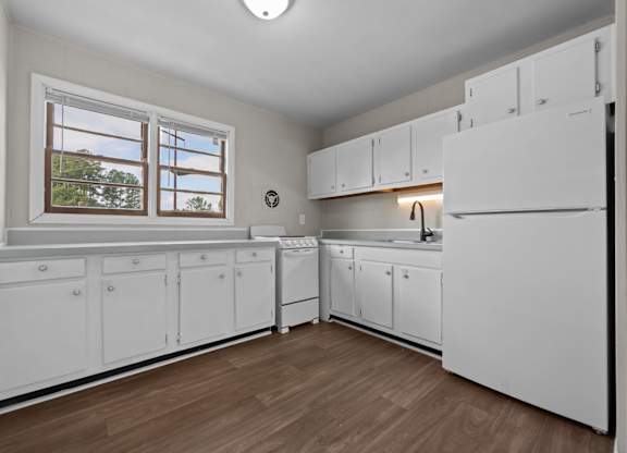 A kitchen with white cabinets and a window.