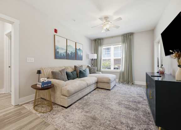A living room with a beige couch, a grey rug, and a painting on the wall.
