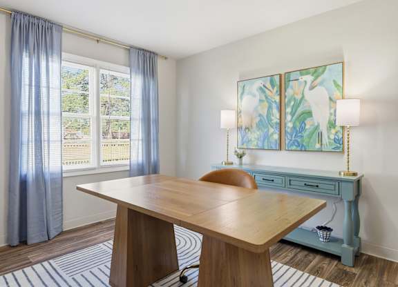 A room with a wooden table and a painting on the wall.