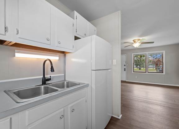 A kitchen with white cabinets and a stainless steel sink.