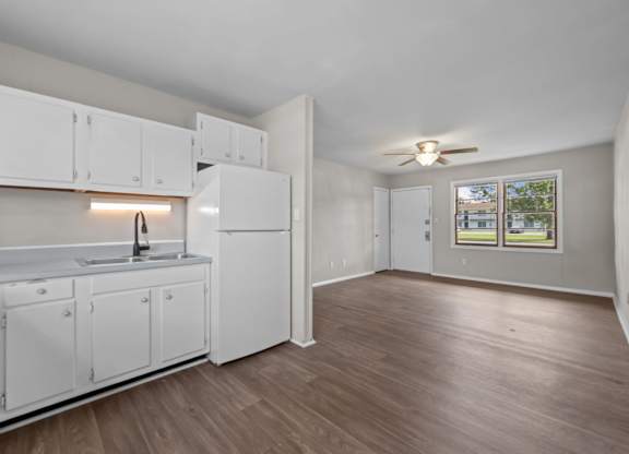 A kitchen with white cabinets and a wooden floor.