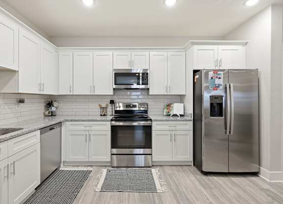 A modern kitchen with white cabinets and stainless steel appliances.