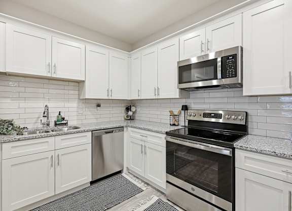 A kitchen with white cabinets and a black stove top oven.