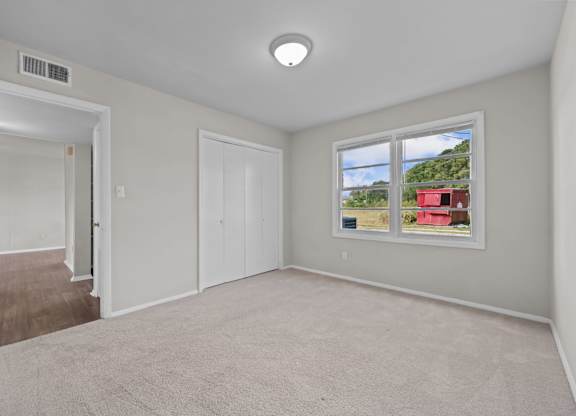 A room with a window showing a red building outside.