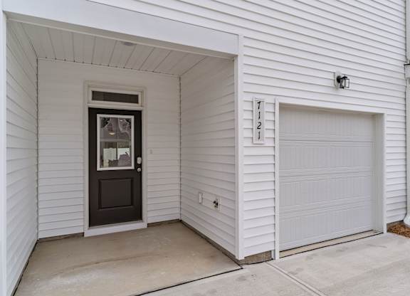 A white house with a black door and a garage door.