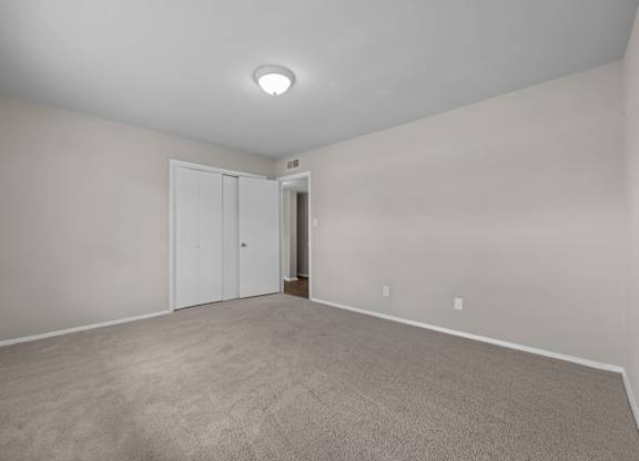 A room with a carpeted floor and a white ceiling with a light fixture.