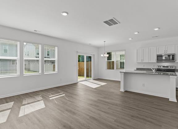 the living room and kitchen of a new home with white walls and wood floors