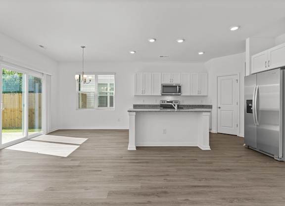 a white kitchen with stainless steel appliances and a door to a patio