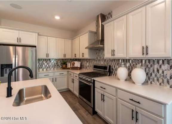 A kitchen with white cabinets and a black and white tiled backsplash.