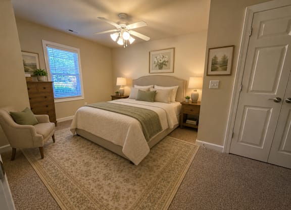 A bedroom with a bed, chair, and ceiling fan.