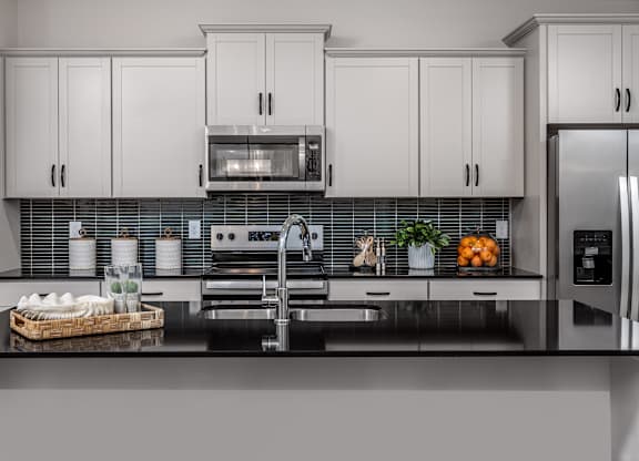 A modern kitchen with white cabinets and a black countertop.