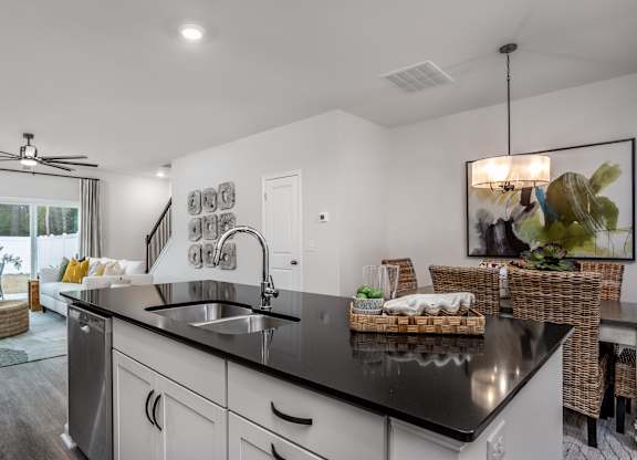 A modern kitchen with a black countertop and stainless steel appliances.
