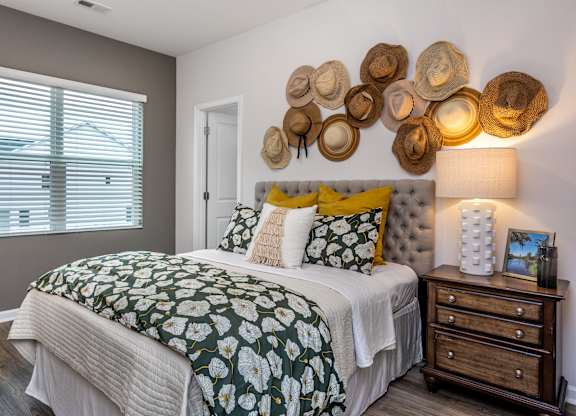 A bedroom with a bed, nightstand, and hat decorations on the wall.