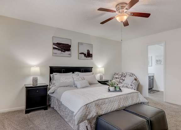 A bedroom with a bed, nightstand, and a ceiling fan.