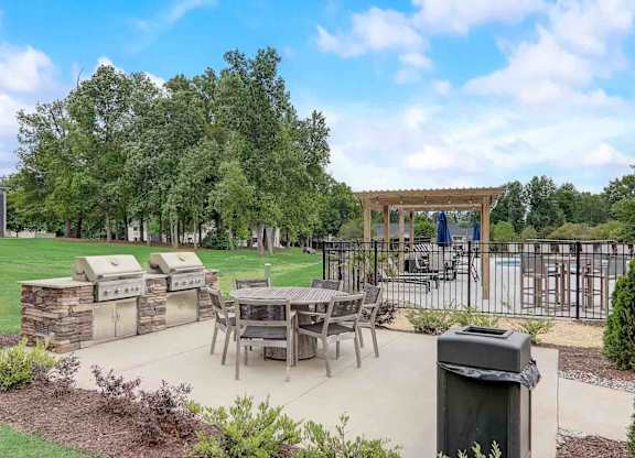 A backyard with a picnic table and a grill.